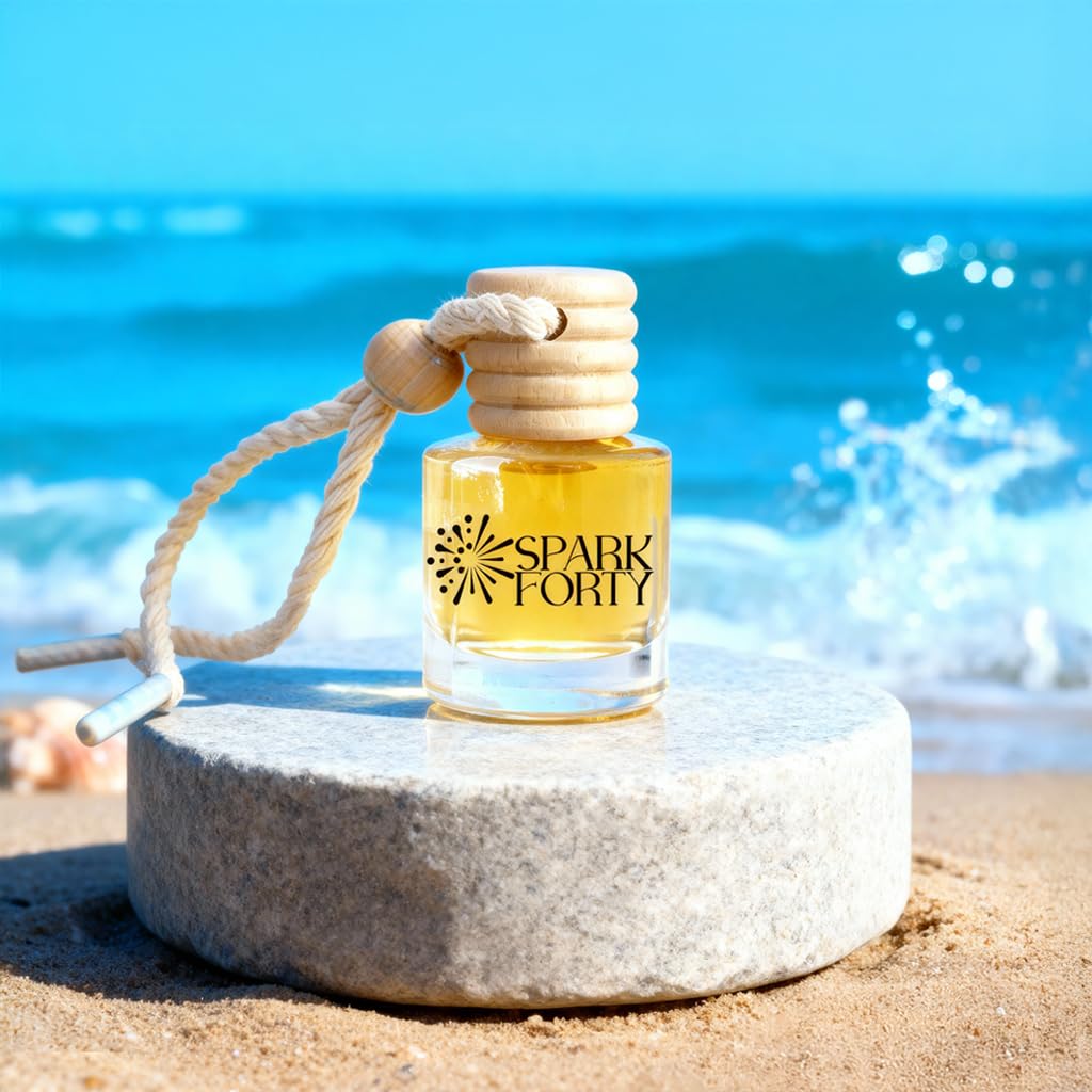 Sparkforty Ocean car air freshener featuring a blue glass fragrance bottle with a natural wooden diffuser cap and cotton hanging rope displayed on a stone pedestal at the beach, showcasing a premium long-lasting aquatic car fragrance inspired by the ocean.